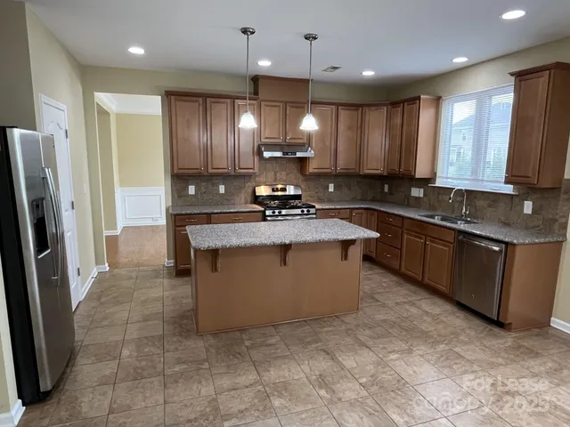 a kitchen with granite countertop stainless steel appliances a sink stove and cabinets