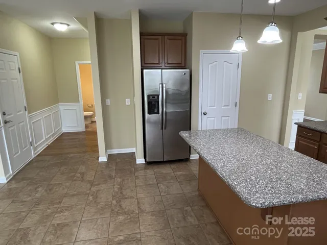 a view of kitchen with granite countertop cabinets and chandelier