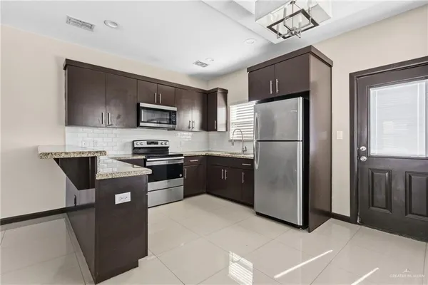 a kitchen with granite countertop stainless steel appliances a refrigerator a stove a sink a microwave and cabinets