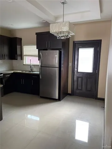 a view of kitchen with granite countertop cabinets and refrigerator