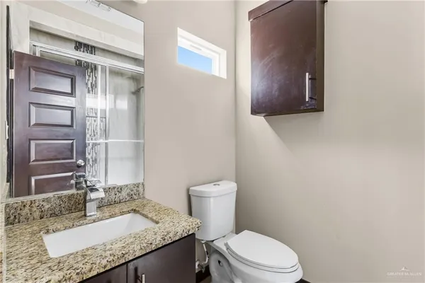 a bathroom with a granite countertop sink mirror vanity and toilet