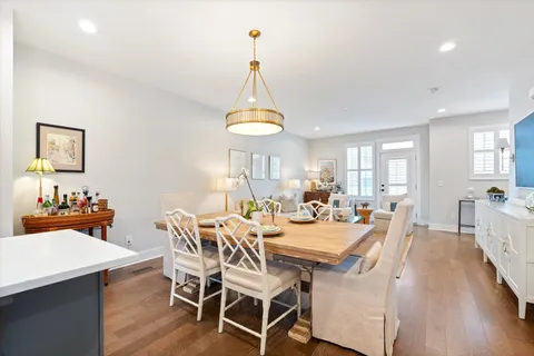a view of a dining room and livingroom with furniture wooden floor a chandelier