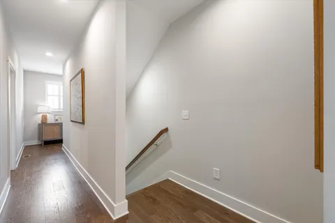 a view of a hallway with wooden floor and a bathroom