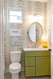 a bathroom with a toilet sink vanity mirror and next to a window