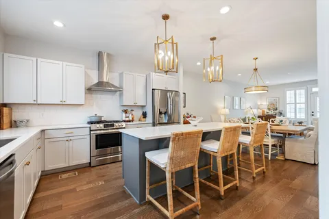 a kitchen with stainless steel appliances a dining table chairs stove and white cabinets