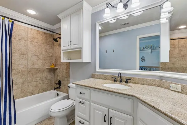 a bathroom with a granite countertop sink a toilet and shower