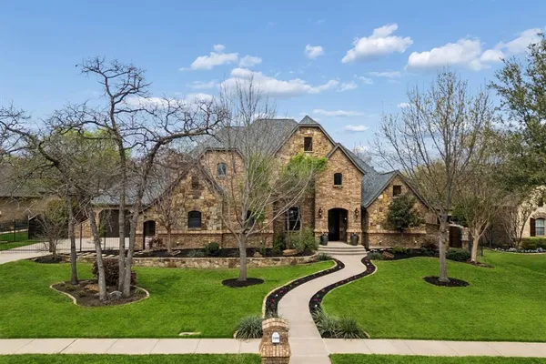 a front view of a house with a garden and trees