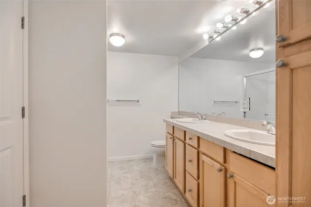 a spacious bathroom with a granite countertop sink a toilet and a shower