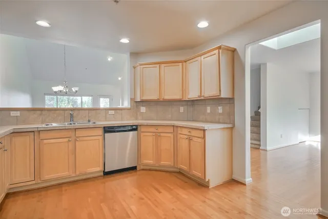 a kitchen with stainless steel appliances granite countertop a stove a sink and a refrigerator with wooden floor