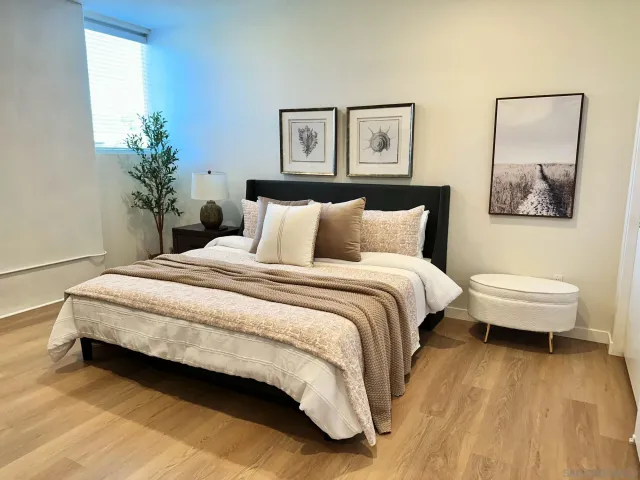 a bedroom with a bed lamp and paintings on the wall
