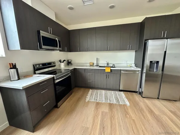 a kitchen with stainless steel appliances granite countertop a sink dishwasher a stove and a refrigerator