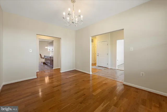 a view of an empty room with wooden floor and a ceiling fan