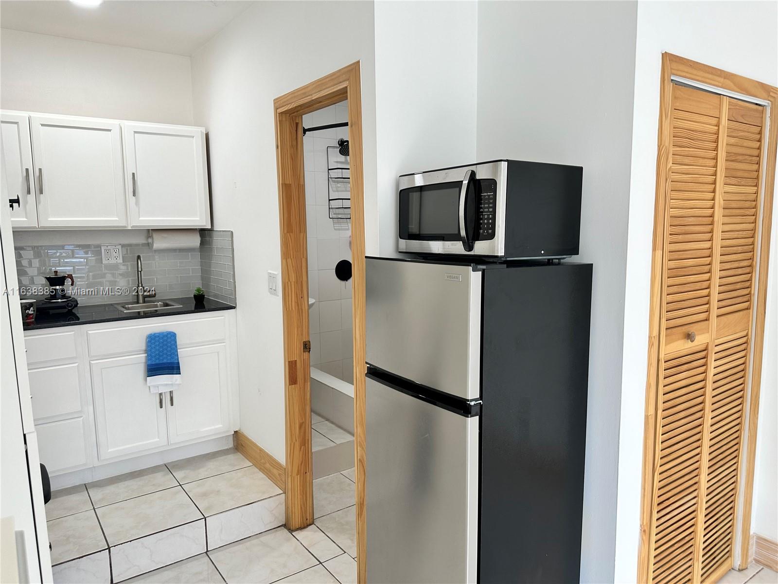 15501 Southwest 143rd Avenue, Unit 15501 Miami, FL 33177 - Photo 8 of 11 a kitchen with a refrigerator and cabinets