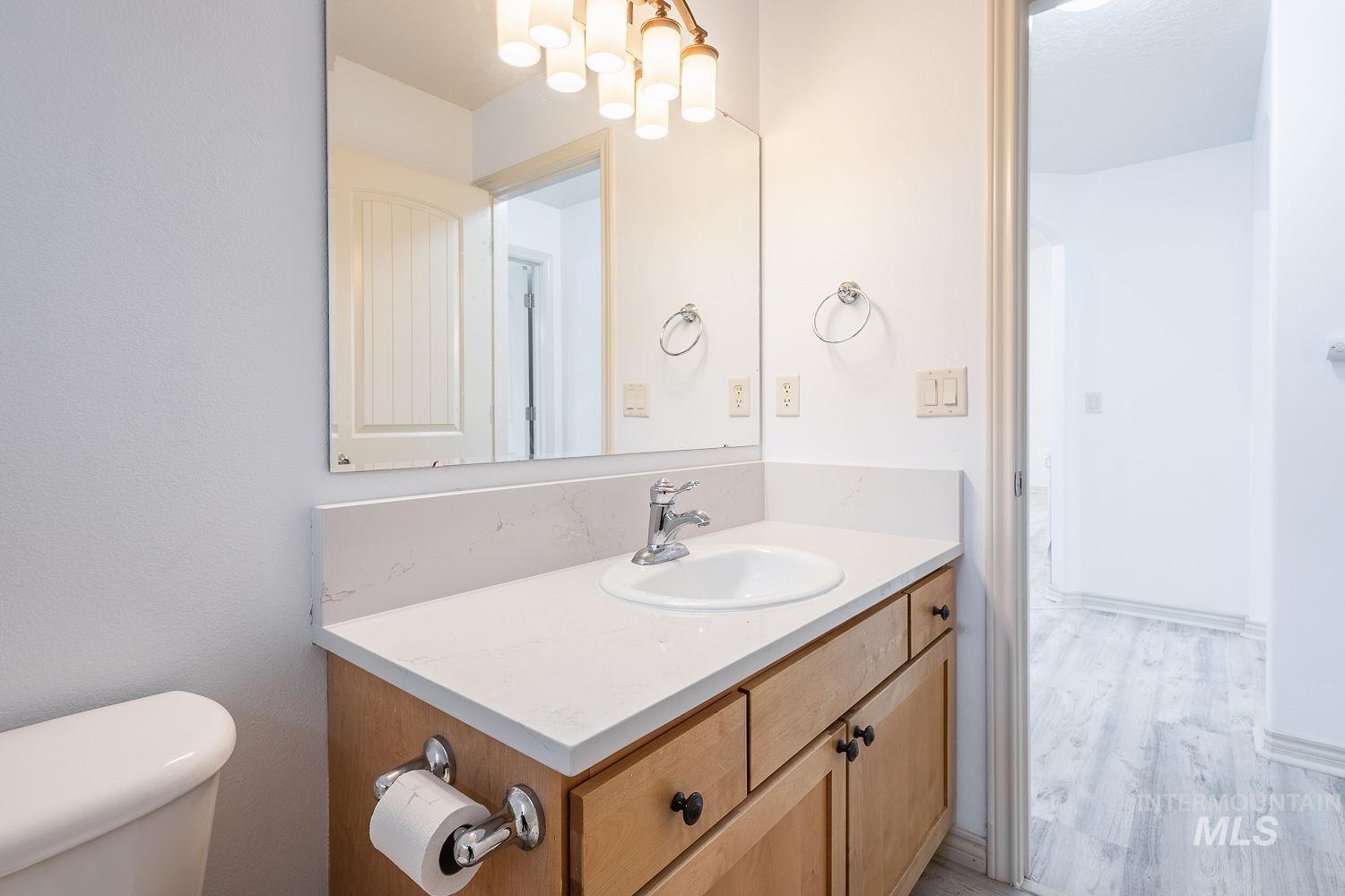 4227 North Rhodes Avenue Meridian, ID 83646 - Photo 18 of 27 Vanity featuring a white countertop with integrated sink, wood-finish cabinetry, and chrome fixtures