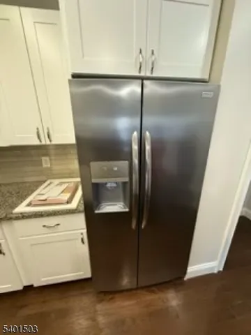an empty room with wooden floor and a kitchen