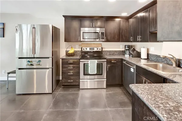 a kitchen with stainless steel appliances granite countertop a stove a sink dishwasher and a refrigerator