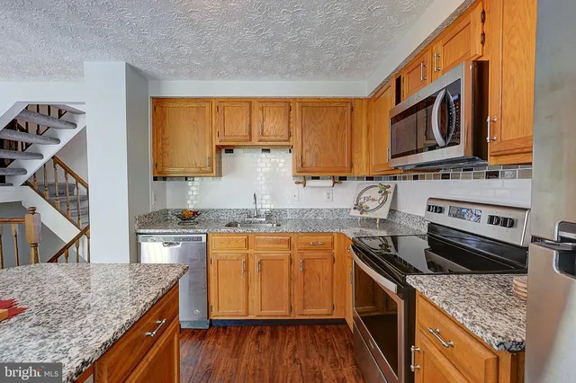 a kitchen with stainless steel appliances granite countertop wooden cabinets and a stove top oven