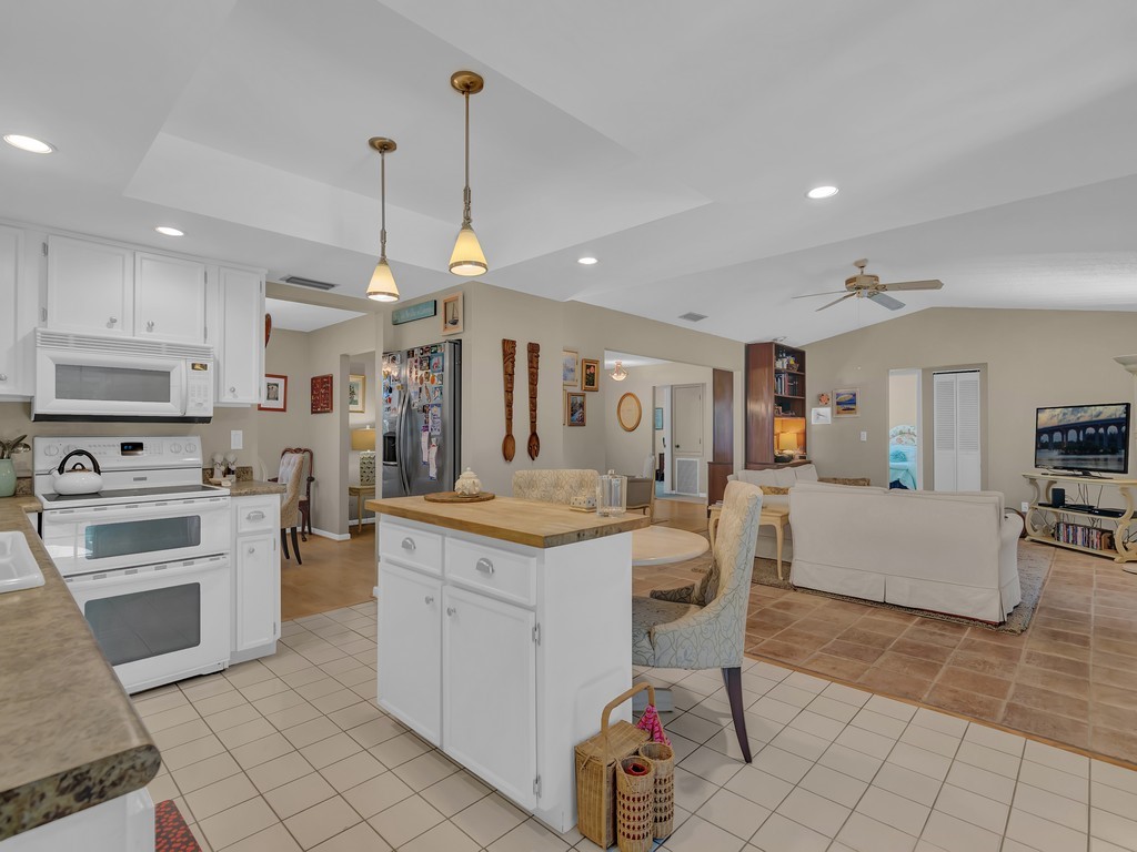 1045 Clipper Road Vero Beach, FL 32963 - Photo 11 of 36 a kitchen with stainless steel appliances kitchen island granite countertop a stove a sink a dining table and chairs with wooden floor