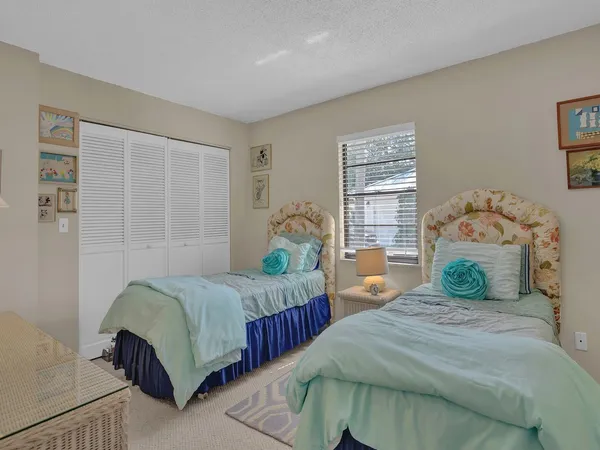 a bedroom with two beds and next to a window