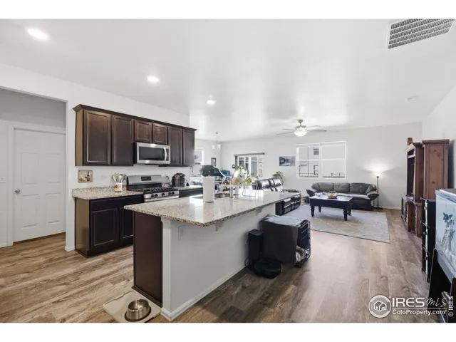 a kitchen with stainless steel appliances a sink a stove a refrigerator cabinets and a dining table