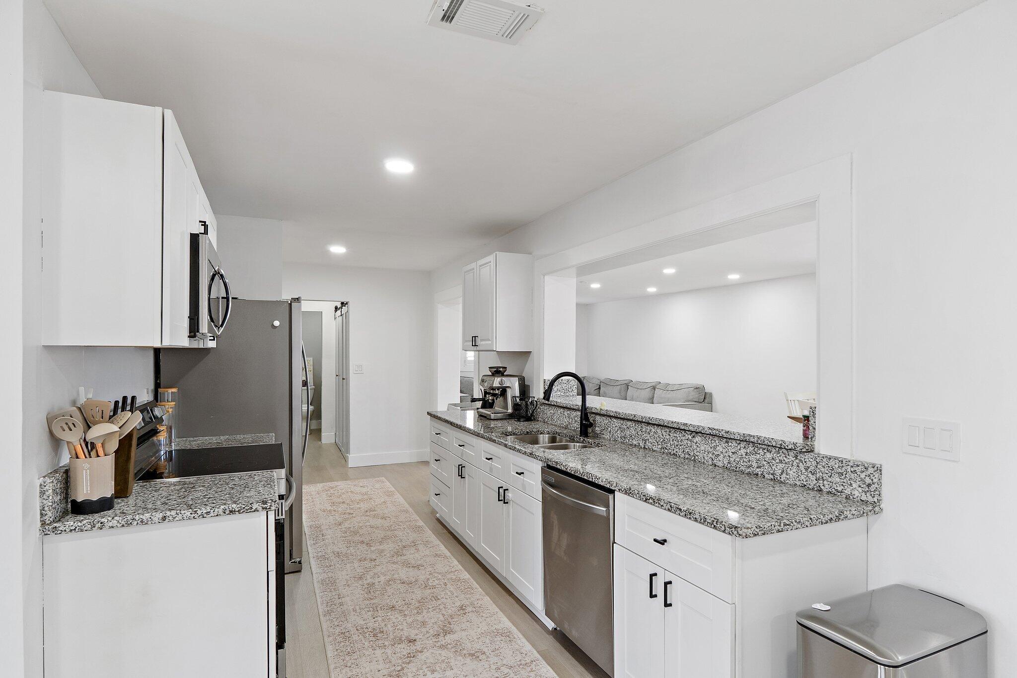 1851 Southeast Jackson Street Stuart, FL 34997 - Photo 15 of 61 a kitchen with stainless steel appliances granite countertop a sink stove and refrigerator
