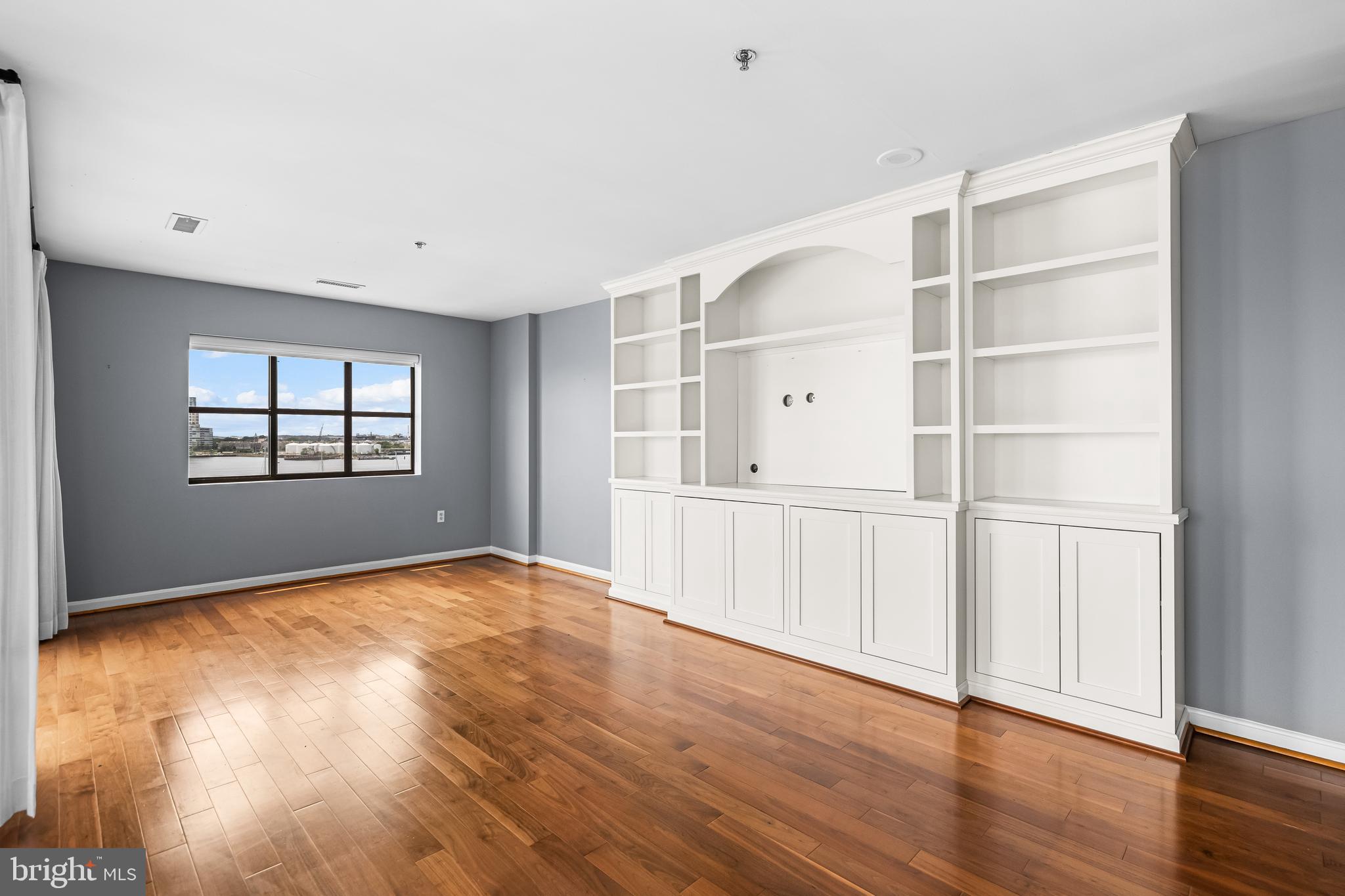 2702 Lighthouse Point East, Unit 638 Baltimore, MD 21224 - Photo 26 of 72 a view of an empty room with a window and wooden floor