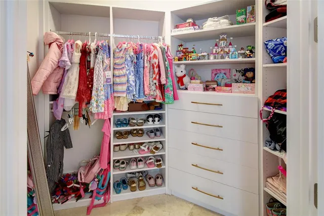 a view of walk in closet with clothes and shoes