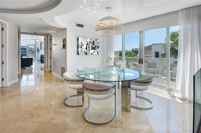 a dining room with wooden floor a chandelier a glass table and chairs