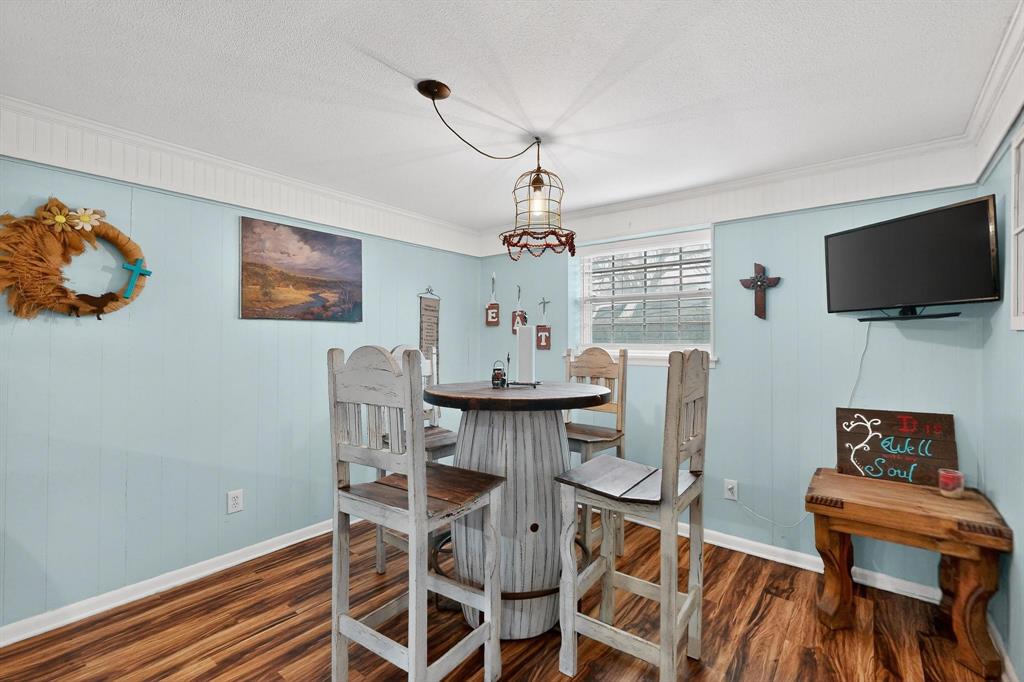 202 Senter Valley Road Irving, TX 75060 - Photo 13 of 32 Dining area featuring wood-finish flooring, light blue paneling, white crown molding, and a visible window with horizontal blinds