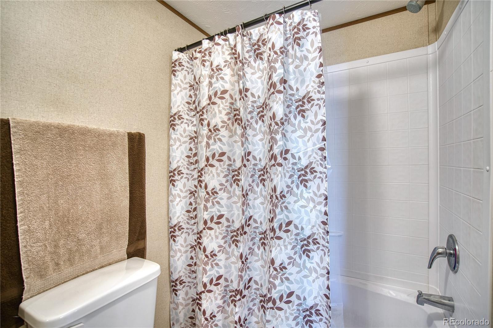 218 Grape Street Hudson, CO 80642 - Photo 14 of 17 a bathroom with a shower curtain and a toilet