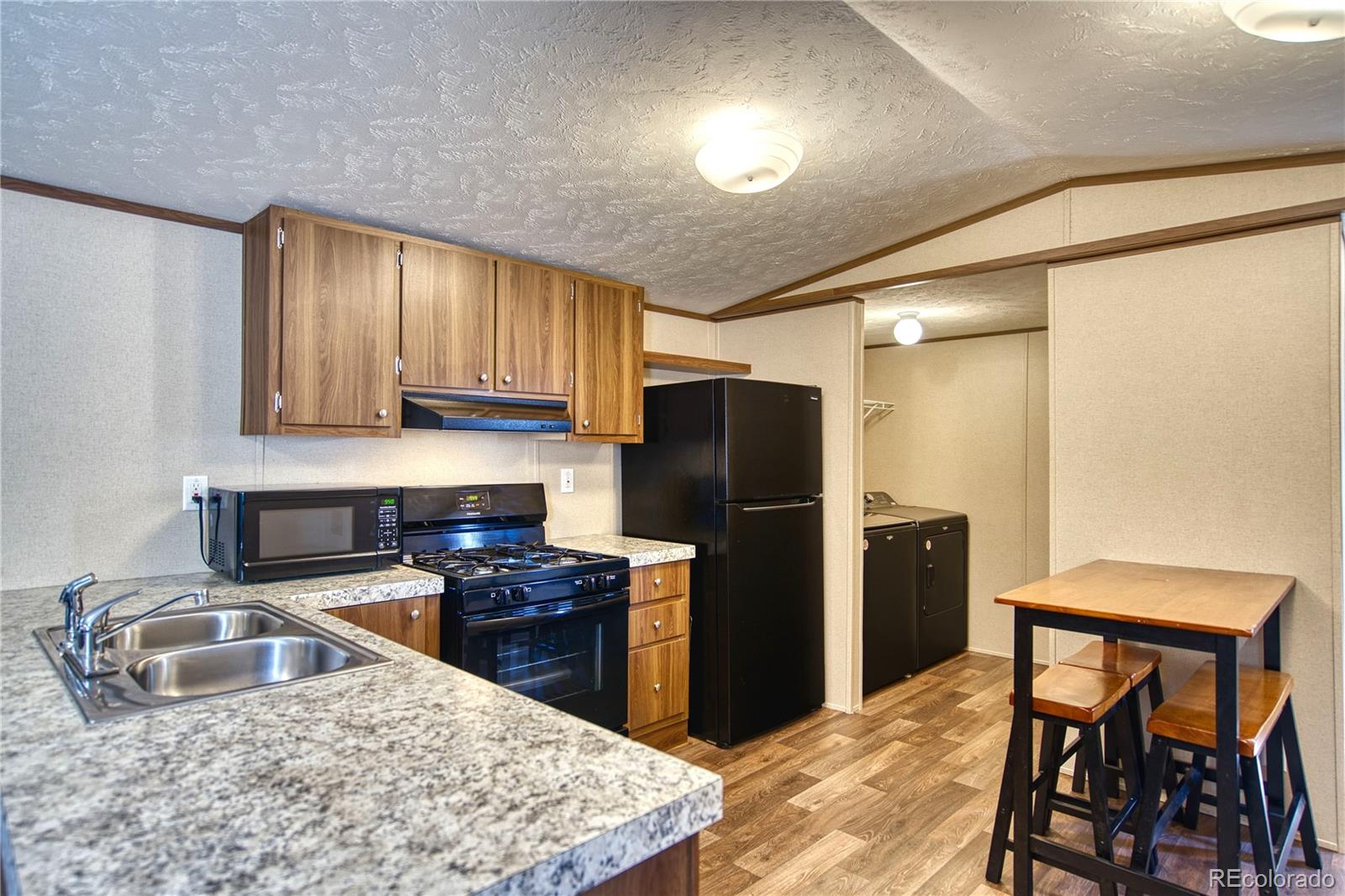 218 Grape Street Hudson, CO 80642 - Photo 3 of 17 a kitchen with stainless steel appliances granite countertop a refrigerator a sink a stove and island