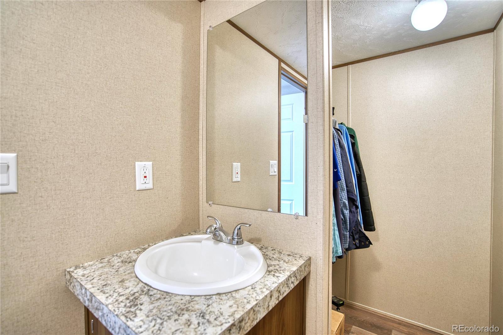 218 Grape Street Hudson, CO 80642 - Photo 8 of 17 a bathroom with a granite countertop sink and a mirror