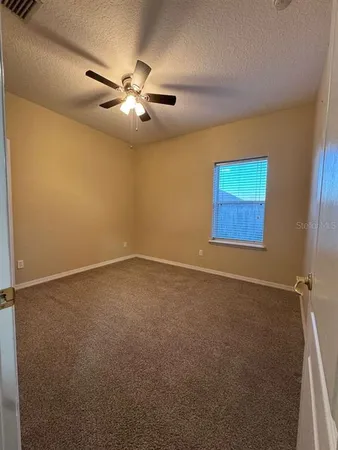 an empty room with windows and fan