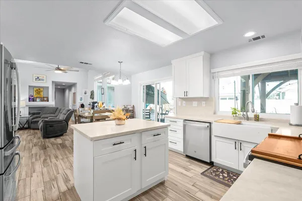 a large white kitchen with a stove a sink a dining table and chairs