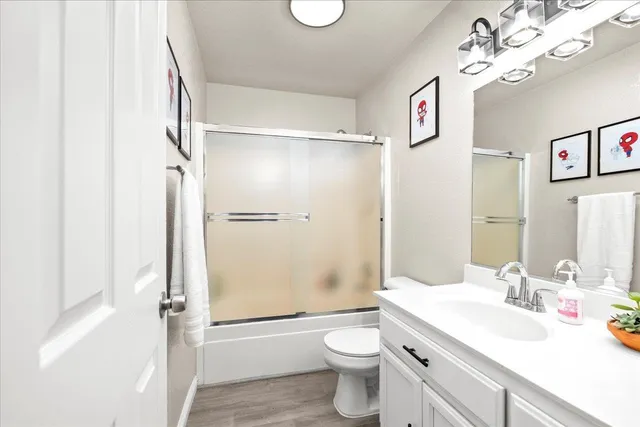 a bathroom with a granite countertop shower sink vanity mirror and toilet