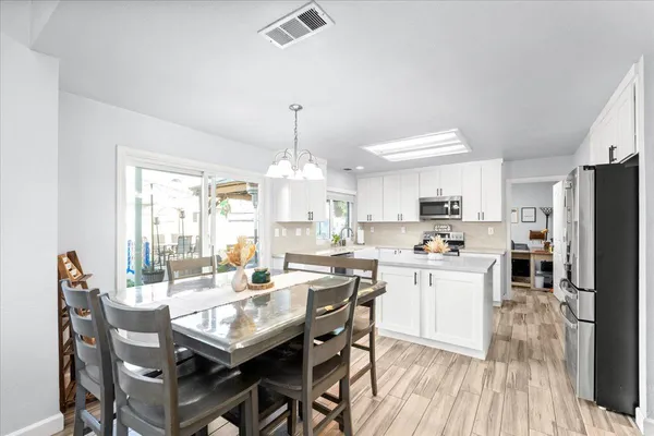 a kitchen with a dining table chairs and refrigerator