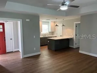 a living room with kitchen island granite countertop wooden floor and a sink