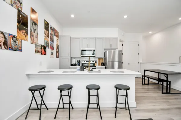 a kitchen with stainless steel appliances a table chairs and a refrigerator