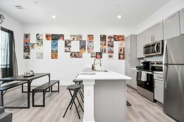 a kitchen with stainless steel appliances kitchen island granite countertop a refrigerator and a stove top oven with wooden floor