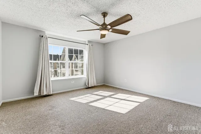 an empty room with a ceiling fan and carpet
