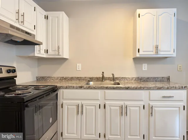 a kitchen with granite countertop a sink a stove and cabinets
