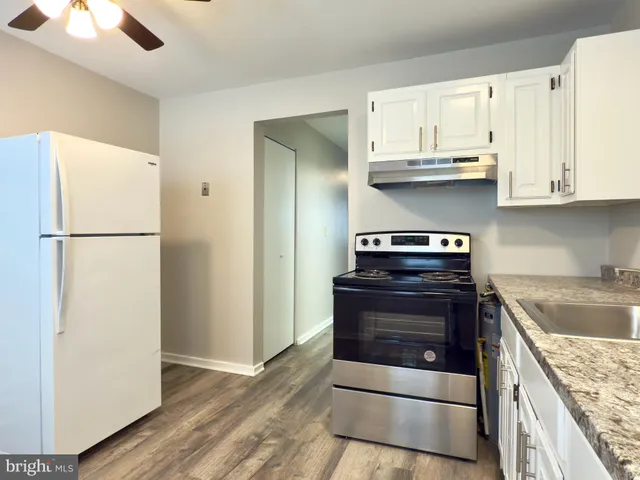 a kitchen with granite countertop a refrigerator sink and cabinets