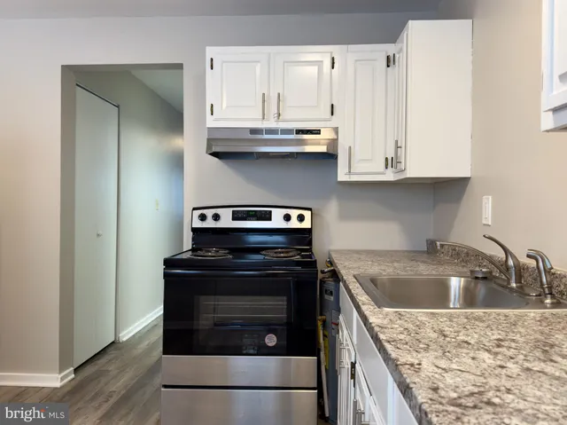 a kitchen with granite countertop a sink dishwasher stove and cabinets