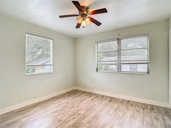 a view of an empty room with window and wooden floor