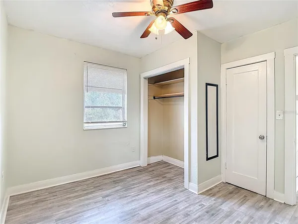 an empty room with wooden floor closet and windows