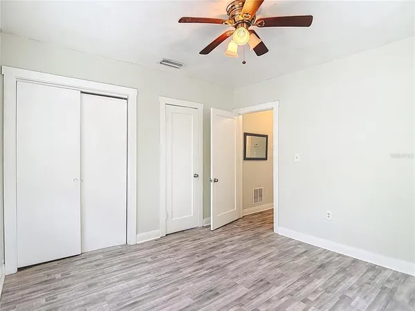 an empty room with wooden floor closet and chandelier fan