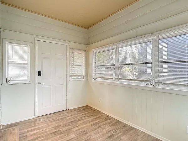 a view of an empty room with wooden floor and a window