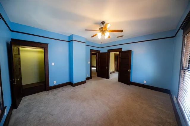 an empty room with closet and a chandelier fan