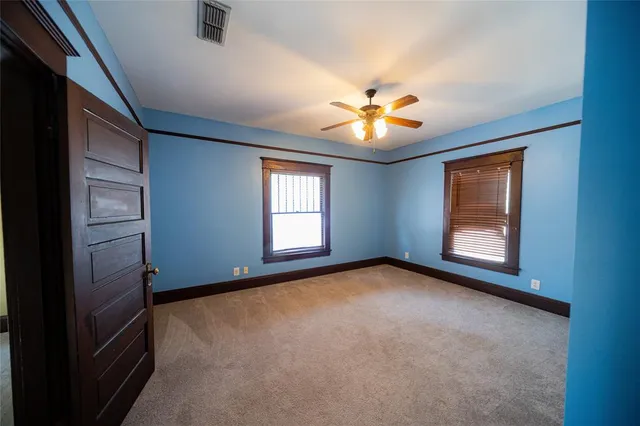 an empty room with windows and chandelier fan