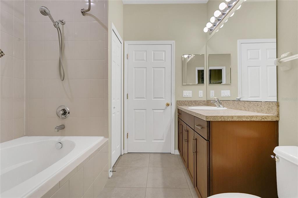 543 Rainbow Springs Loop Groveland, FL 34736 - Photo 14 of 26 a bathroom with a granite countertop sink a mirror and a bathtub